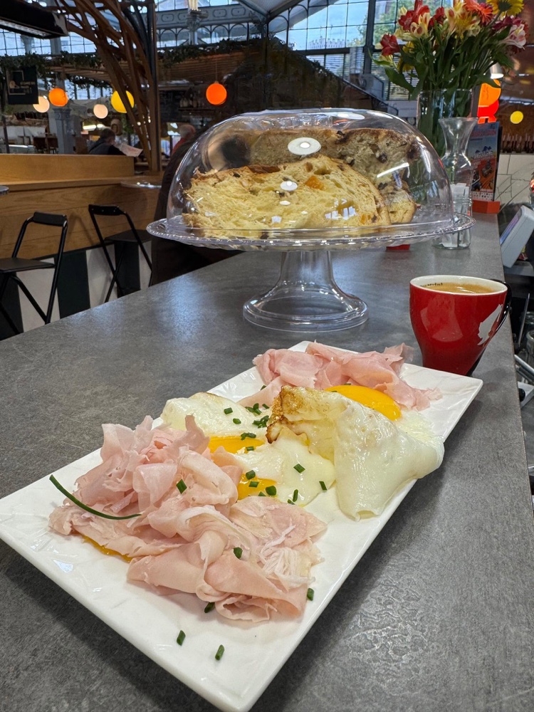 Assiette de jambon italien, œufs et tranches de pandoro servie au comptoir, avec un café